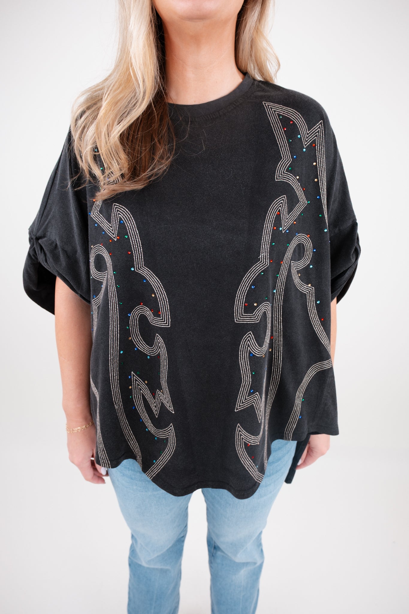 Person wearing a black oversized shirt with decorative boot stitch patterns on a white background
