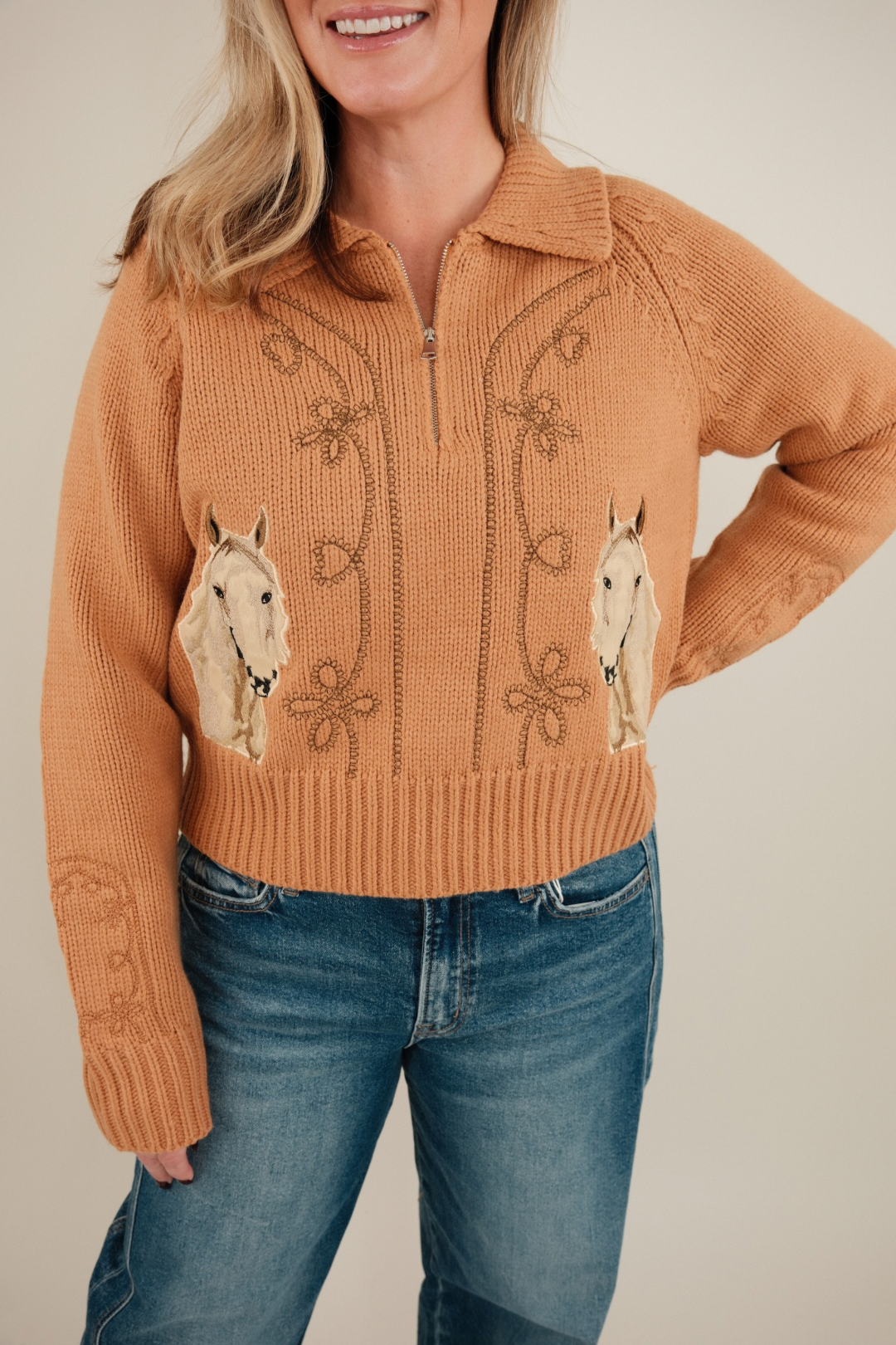 Close-up of Sundance Embroidered Quarter-Zip Sweater highlighting horse motif, floral embroidery, and cute bow accents on elbows.
