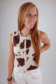 Woman wearing a cow print sleeveless top against a plain background