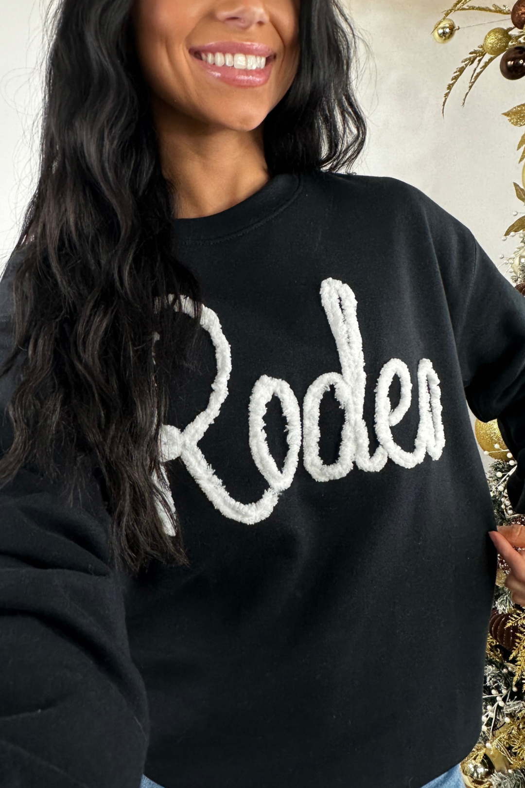 Person wearing a black sweatshirt with 'Roden' text, standing against a decorative background.