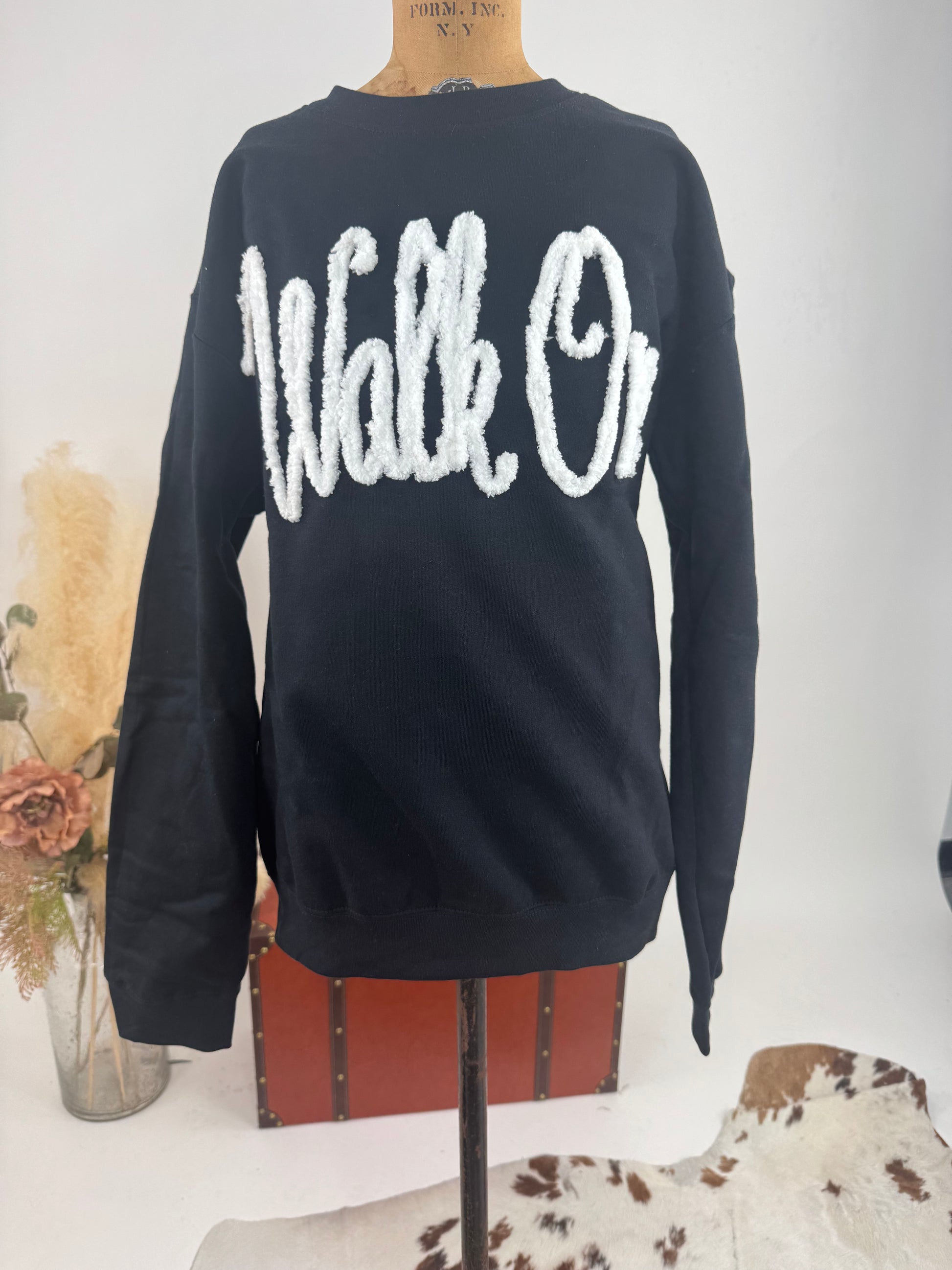 Black sweatshirt with 'Walk On' text on a mannequin against a neutral background