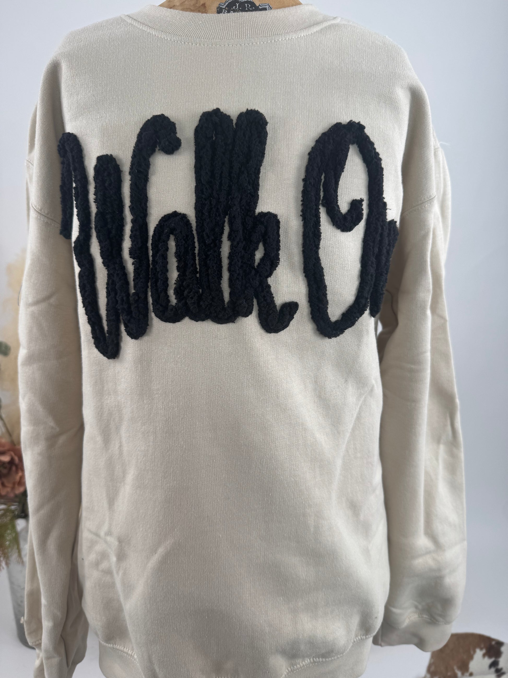Beige sweater with black 'Walk On' text on the back against a neutral background