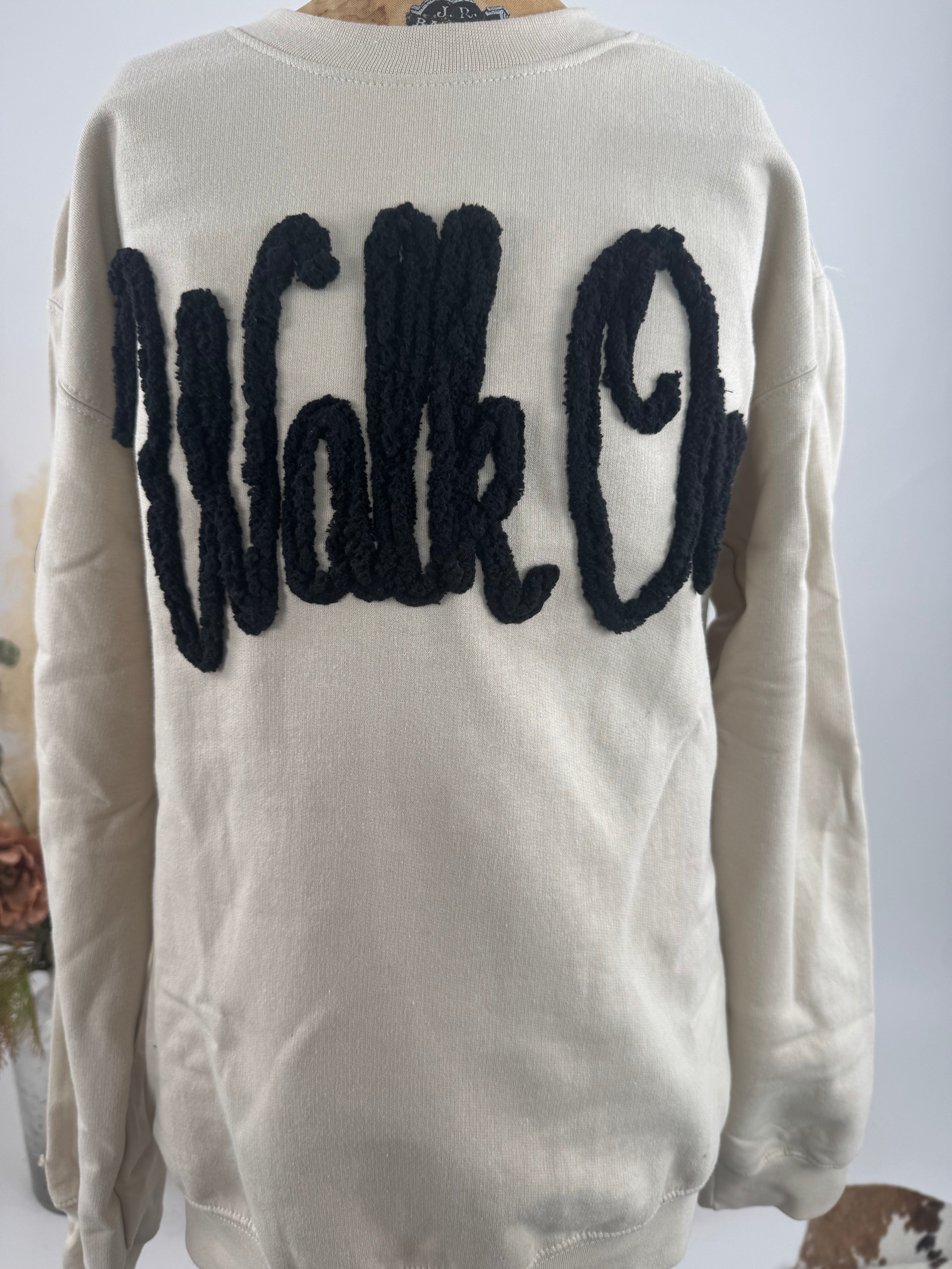 Beige sweater with black 'Walk On' text on the back against a neutral background