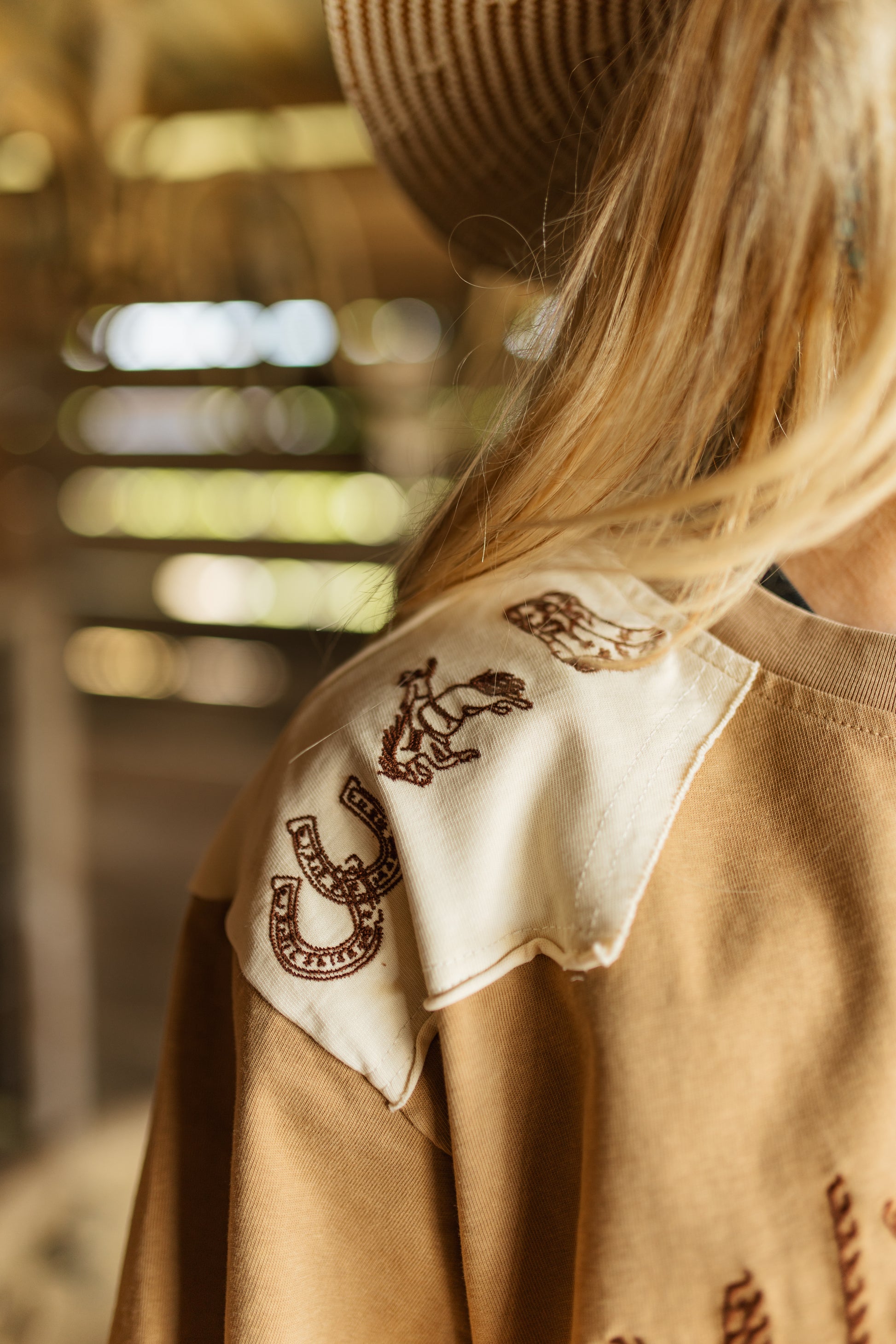 Close-up of a person wearing a brown shirt with embroidered designs, blurred background