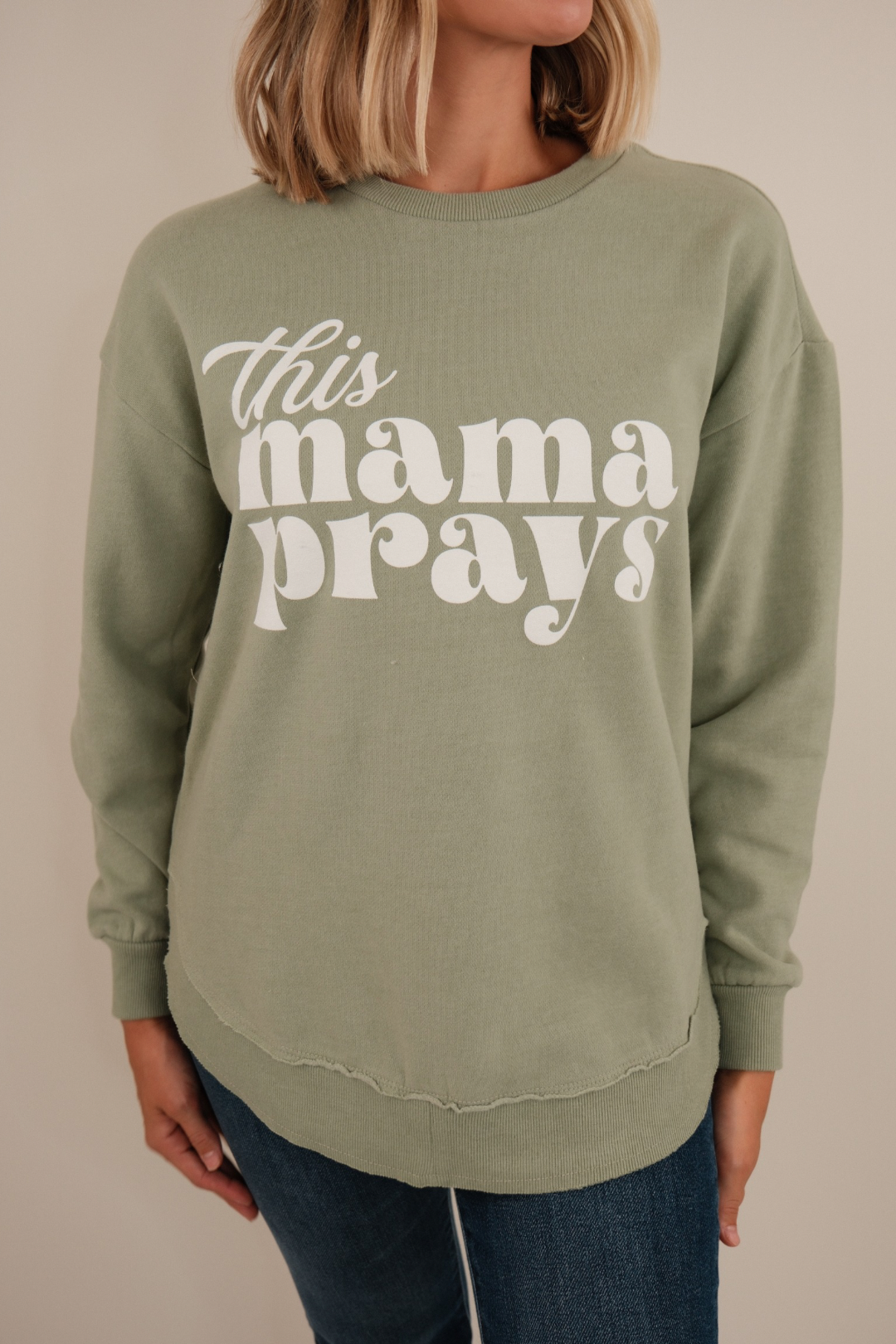 Front view of This Mama Prays Poncho Fleece in sage knit with bold text, rounded hem and relaxed western fit.