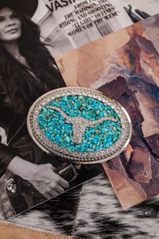 Turquoise belt buckle with silver trim on a textured surface