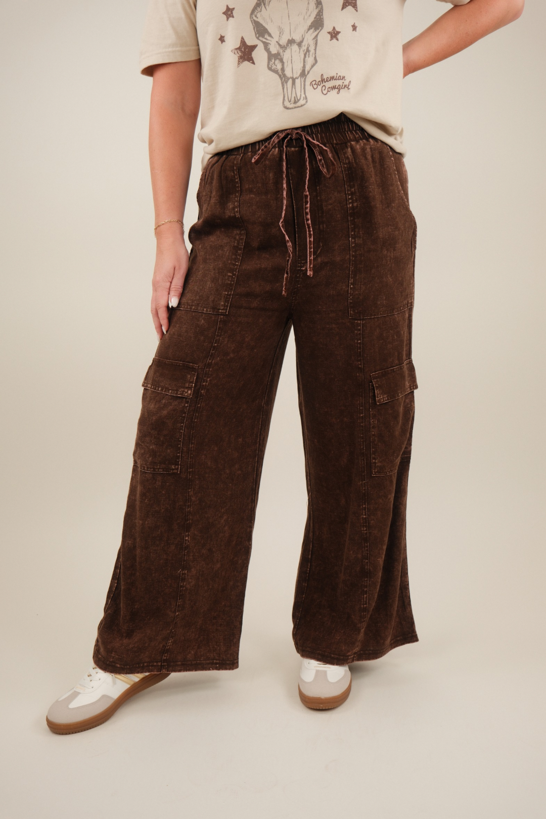 Model wearing brown mineral‑washed linen‑blend cargo pants with elastic drawstring waist and flap cargo pockets down the legs