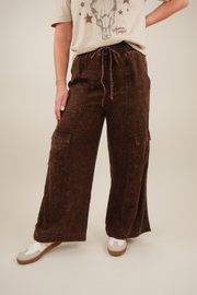 Model wearing brown mineral‑washed linen‑blend cargo pants with elastic drawstring waist and flap cargo pockets down the legs
