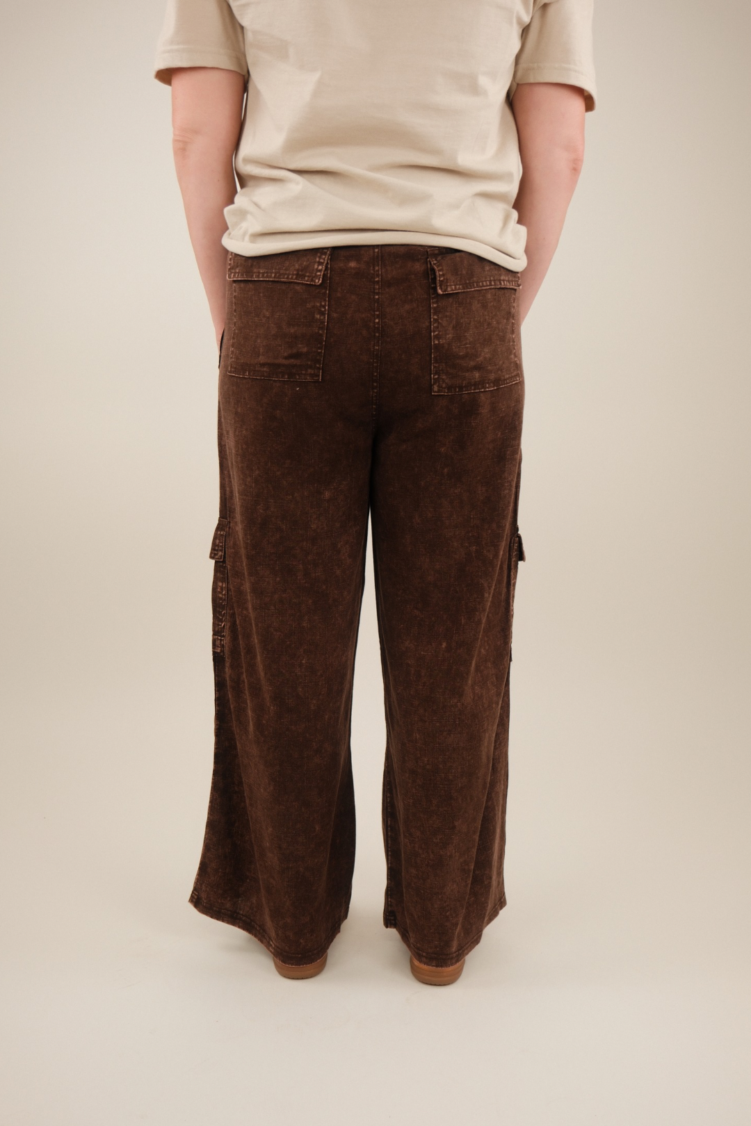 Rear view showing straight‑leg silhouette and relaxed fit of brown washed linen cargo pants.