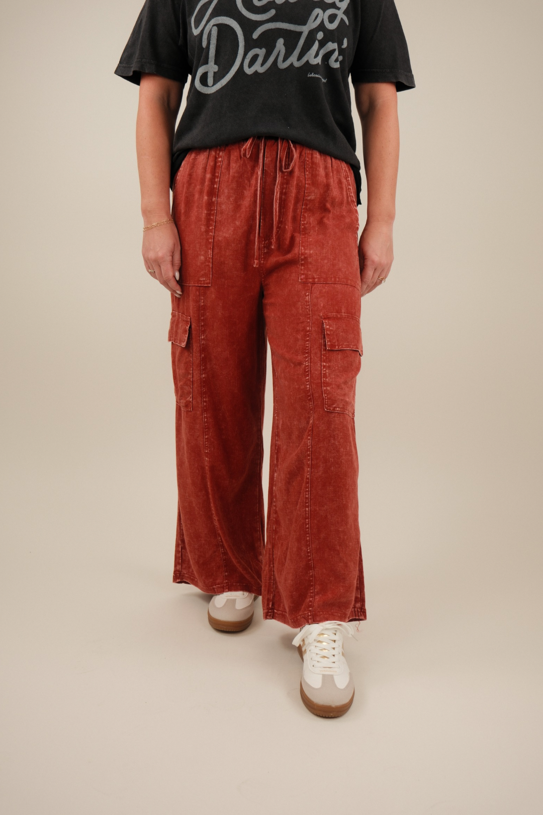 Person wearing a black t-shirt with text and red acid washed linen cargo pants.