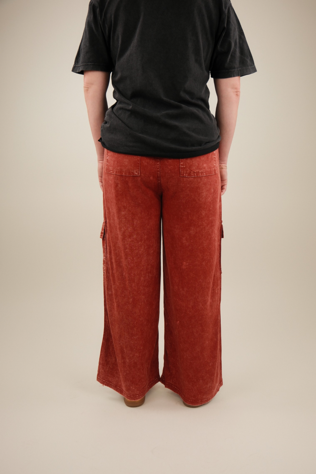 Person wearing red pants and a black shirt on a beige background