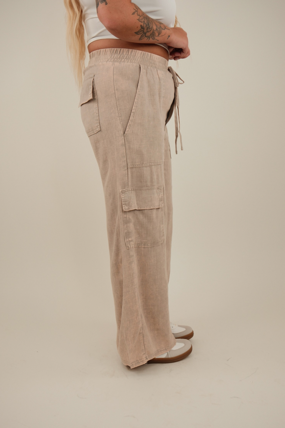 Angled side shot showing mauve linen cargo pants’ relaxed straight leg, flap cargo pockets and adjustable drawstring waistband.