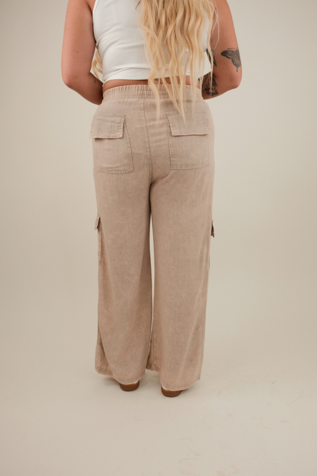 Rear view of mauve linen cargo pants with elastic back waist, gentle mineral‑washed finish and clean straight‑leg silhouette.