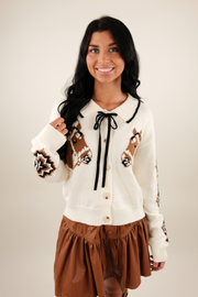 Front view of Western Belle Cardigan, ivory knit with horse head motifs, Aztec sleeves and ruffle collar.