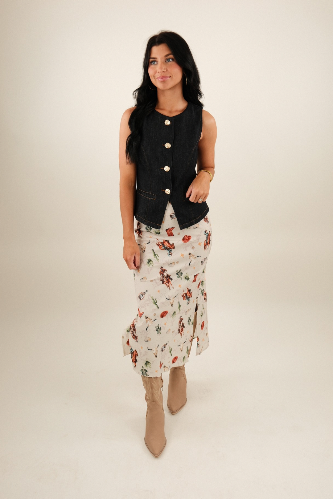 Full body shot of model wearing Western Muse Skirt styled with a denim vest, cream straight silhouette with cowgirl motif print.