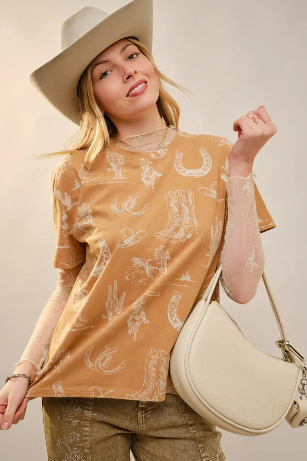 Woman wearing a western patterned shirt and holding a beige handbag against a neutral background