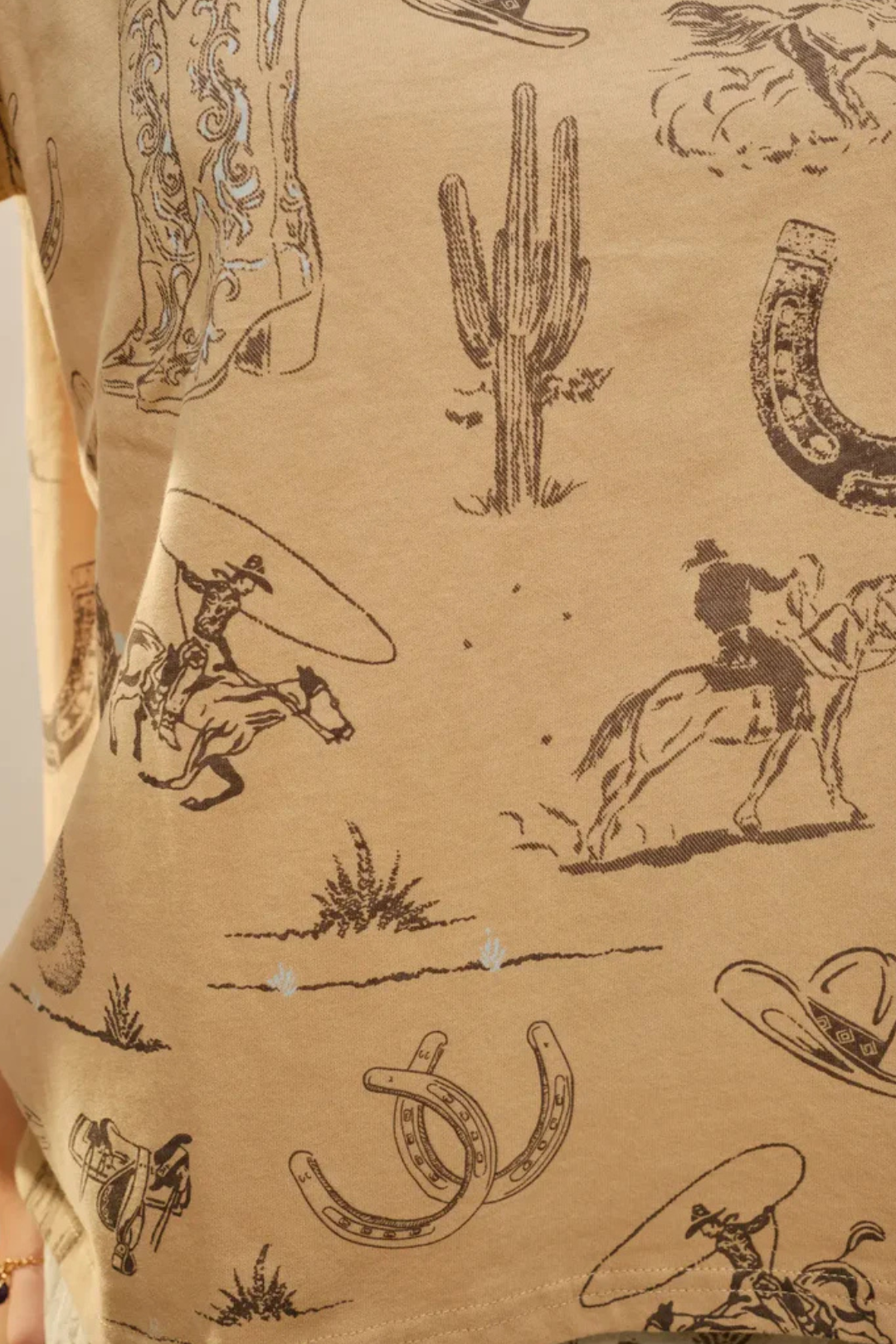 Close-up of a shirt with cowboy-themed graphics on a beige background