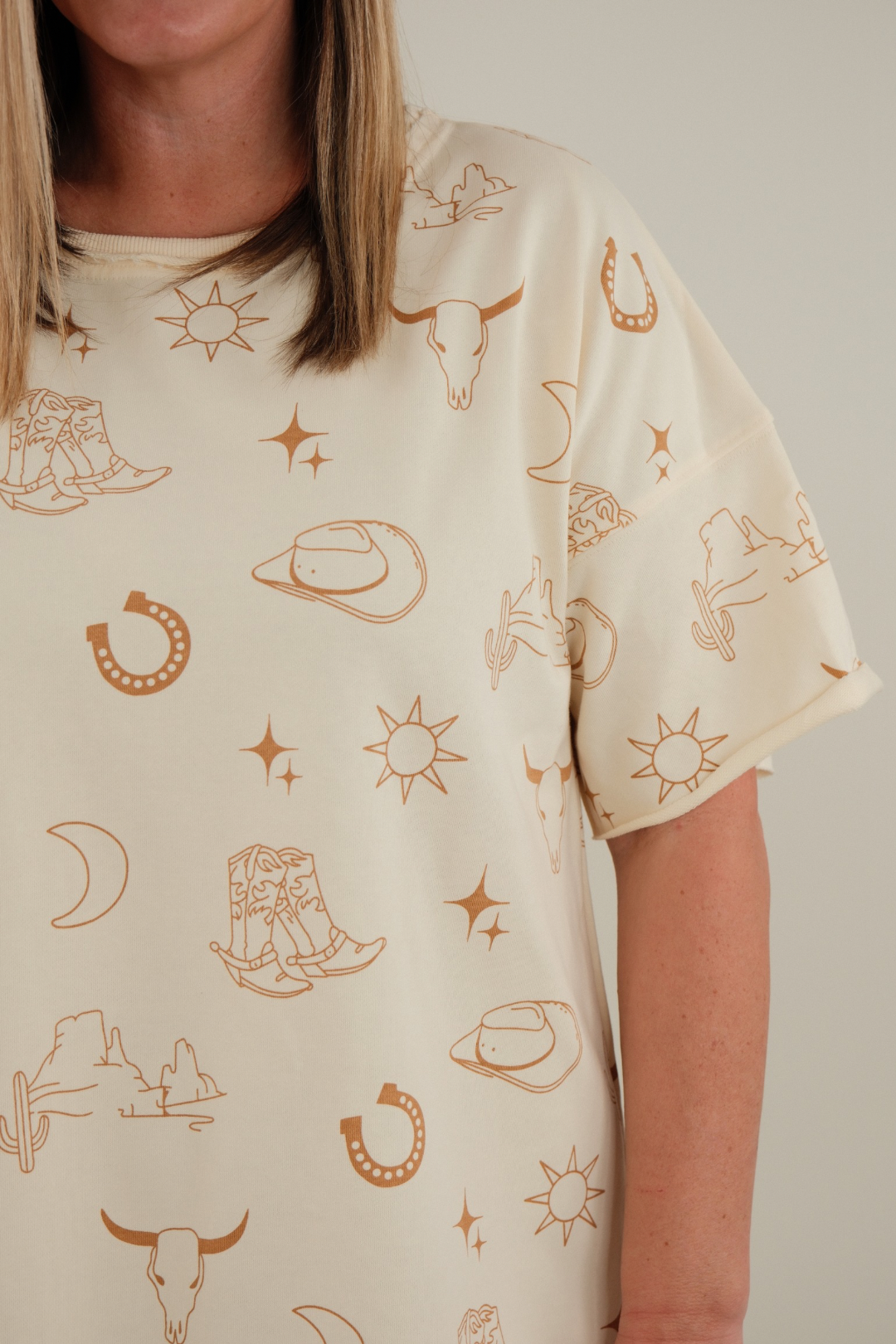 Side profile of women’s Western Skies Tee Dress, cream western t-shirt dress with casual drape and straight silhouette.