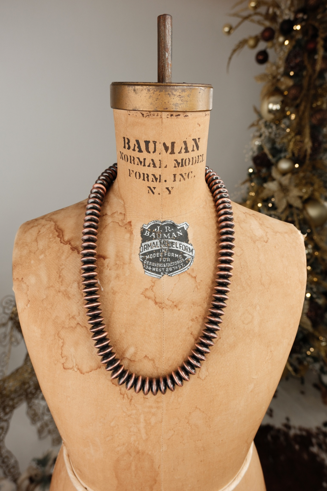 Chunky navajo pearl necklace displayed on a mannequin bust with 'Bauman Normal Model Form, Inc.' label, against a decorative background.