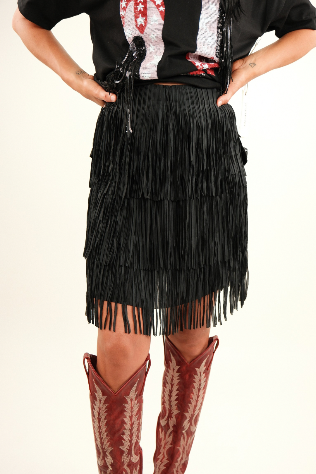 Wild Dunes Fringe Mini Skirt - Black - model wearing fringe skirt that touches the knees paired with red boots