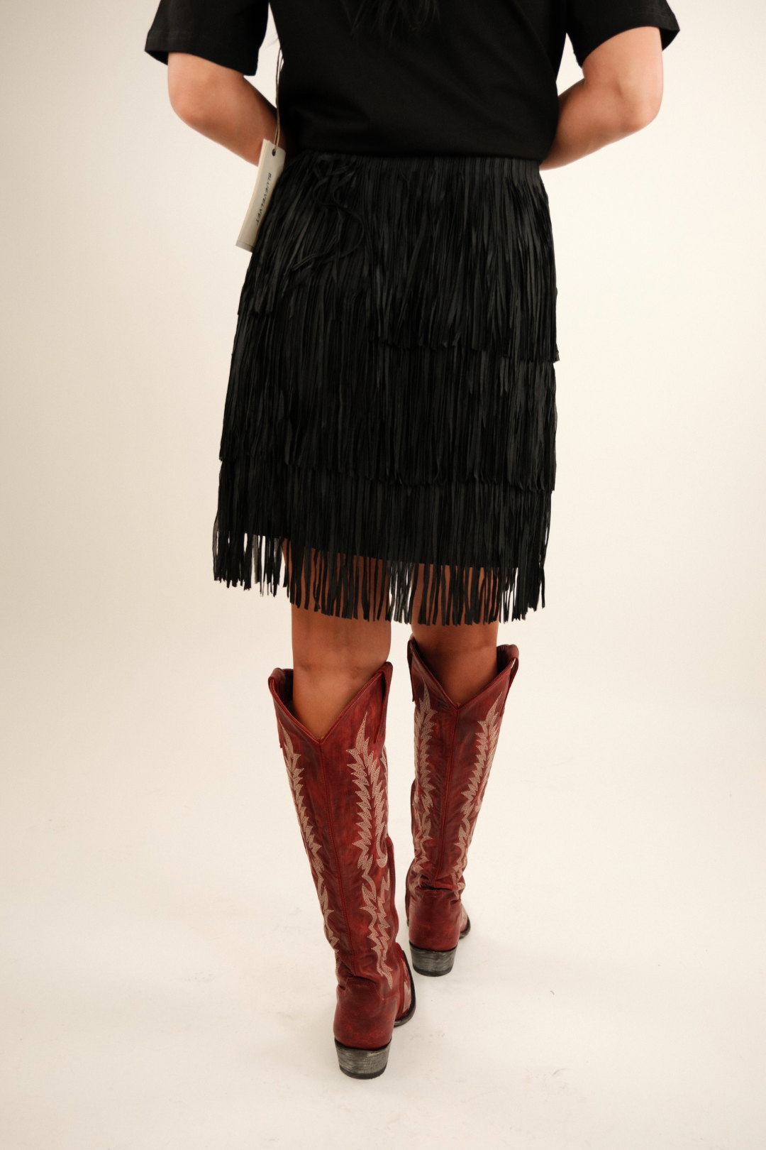 Wild Dunes Fringe Mini Skirt - Black - model wearing fringe skirt that touches the knees paired with red boots