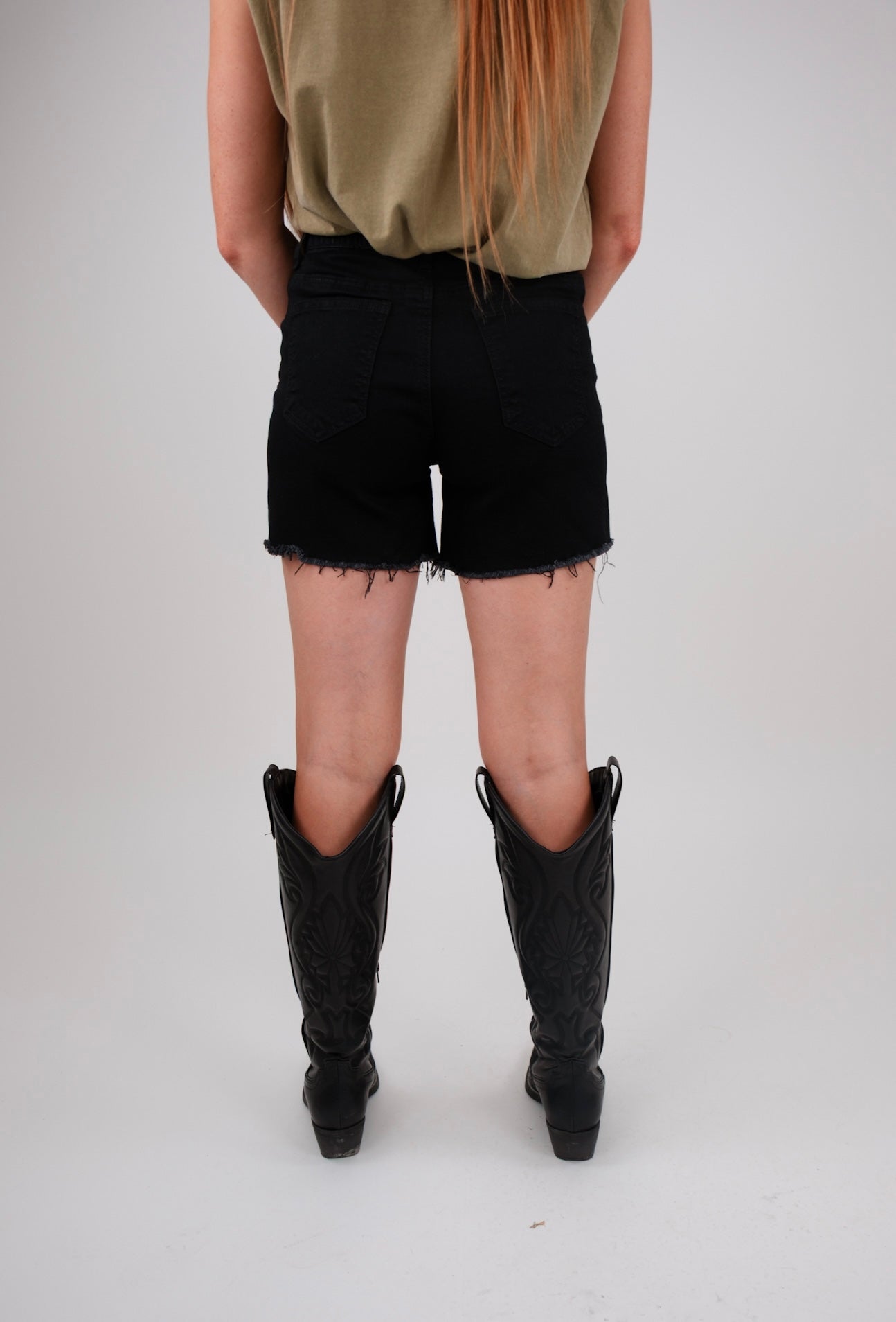 Person wearing black shorts and black boots on a plain background