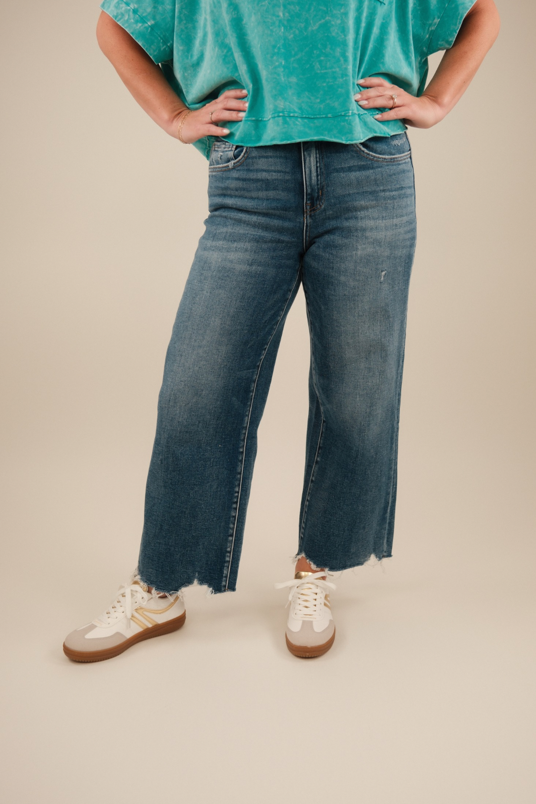 Model wearing mid‑ to high‑rise medium wash denim crop jeans with slight flare at the hem and five‑pocket styling.