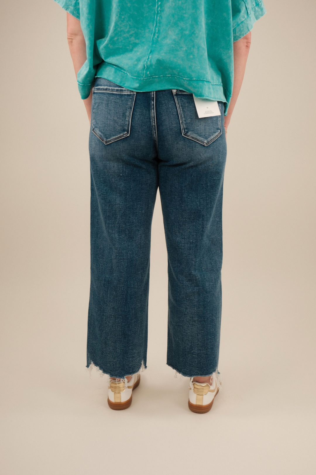 Rear view of medium‑wash cropped jeans showing yoke seam and relaxed flare above the ankle.